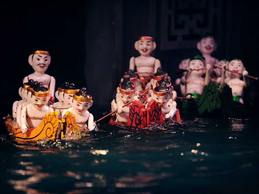 Traditional water puppets performing on a dark stage.