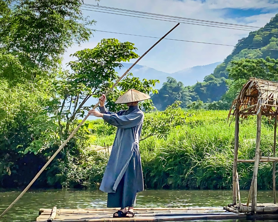 Traveller on a bamboo raft drifting past karst mountains in northern Vietnam.