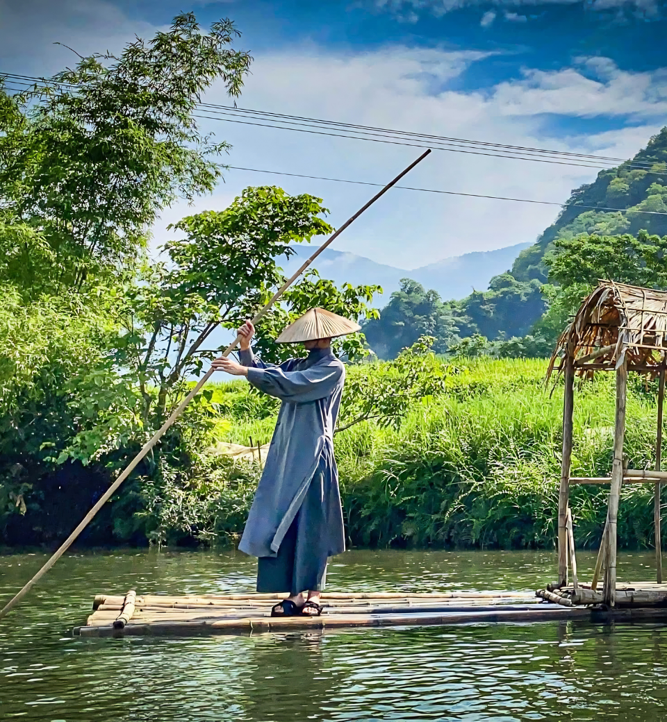 Traveller on a bamboo raft drifting past karst mountains in northern Vietnam.